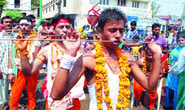 Devotees walk in a procession with their mouths pierced with 