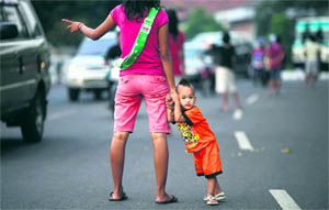 A jobless mother holds her child as she offers to be a "car jockey" in a main street in Jakarta. Many unemployed Indonesians find work as "car jockeys", for which they are paid around 15,000 rupiah ($1.50) to be car passengers, allowing the driver to use a lane dedicated to cars carrying three or more passengers. 