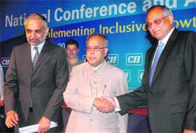 Finance Minister Pranab Mukherjee shakes hands with Venu Srinivasan, outgoing CII president, while incoming CII president Hari Bhartiya looks on at the CIIs national conference in New Delhi