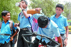 A boy pours water on his head to beat the heat on his return from school, as mercury touched 44 degrees Celsius in Bathinda 