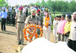 A cop lays wreath on the body of Sangat Singh at Cheekna village