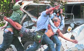 Red Shirt protesters carry a man who was shot during clashes with the police in Bangkok