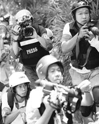 Reporters wearing protective gear cover clashes between Thai soldiers and anti-government protesters in central Bangkok
