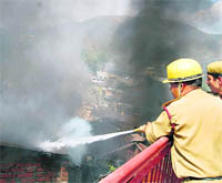 Firemen battle flames in a showroom in Mandi on Sunday.