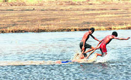Children frolic in water at a Karnal village.