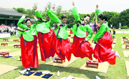 Girls jump in the air to celebrate the 38th Coming of Age Day in front of the 