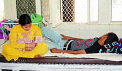 A male attendant enjoys a sound sleep, while a woman patient has to sit on the bed in the gynae ward of the ESI Hospital in Amritsar.