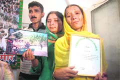 Guddi Devi, sister of cop Devinder Kumar, displays commendation certificates issued to her brother in Jammu on Wednesday.
