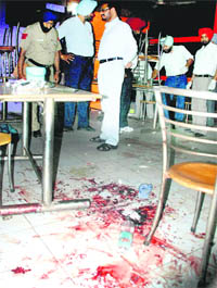 Police officials examine the blood-splattered floor at the Sector 52 tavern in Chandigarh where a cook attacked and grievously wounded three colleagues on Friday.