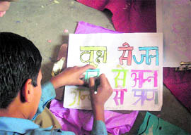 A student writes a slogan about preserving ecology at a government school in Tehri Garhwal on Sunday