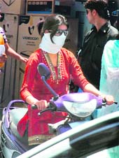 A college girl protects herself from scorching heat as she rides a scooter on a hot day in Jammu on Monday
