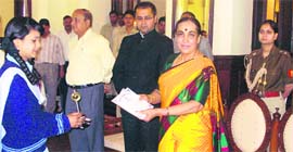 Governor Margaret Alva gives away a prize to a winner of a painting contest held at the Raj Bhawan in Nainital.