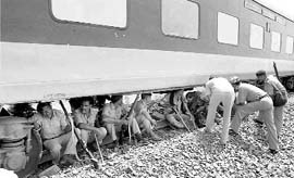 Security personnel take shelter from the sun under the derailed New Delhi-Dibrugarh Rajdhani in Bihars Bhagalpur district on Tuesday.