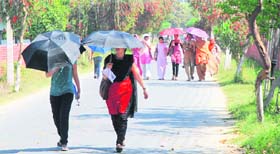 Students use umbrellas to protect themselves from the scorching sun on the Kurukshetra University campus in Kurukshetra.