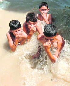 Children take a dip in a pond on the outskirts of Jammu on Thursday.