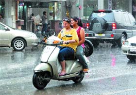 Girls riding a scooter get caught in sudden brief showers in Amritsar on Friday.