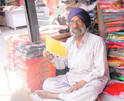 A shopkeeper uses a paper to fan himself during a power cut in Patiala on Sunday.