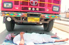 This driver takes a nap under a truck on a hot afternoon in the Narwal area of Jammu