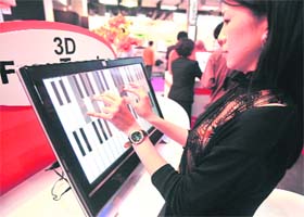 A woman plays music on a flat panel screen using multiple-touch technologies at the Taipei World Trade Centre