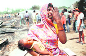 A woman carrying a child wails after losing her belongings in a fire at Adarsh Colony, Sector 53, Chandigarh, on Wednesday. 
