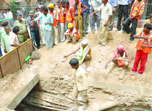 People gather outside a ditch at Curzon Road near Hyderabad House at New Delhi in which four labourers got stuck on Wednesday.