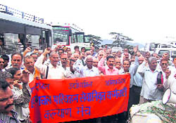 Former employees of the HRTC raise slogans in support of their demands at the main bus stand in Shimla on Thursday