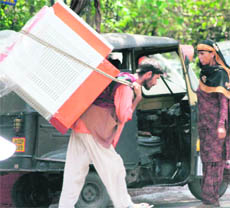 With the temperature soaring in Jammu, a labourer carries a cooler for delivery.