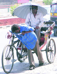 A rickshaw-puller pauses to catch his breath on a hot Thursday afternoon
