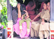 A girl sits in the lap of her mother as she is taken to the police station in Ludhiana on Thursday