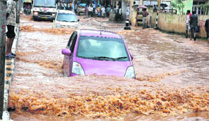 Vehicles pass through a flooded road after a heavy downpour in Guwahati on Thursday.