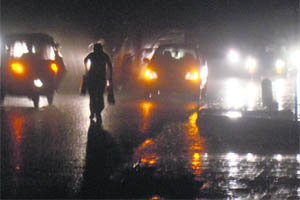 A commuter runs for cover on a water-filled road in Chandigarh on Friday night.