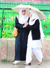 College girls protect themselves from rain, which has been lashing the valley since Thursday night, in Srinagar