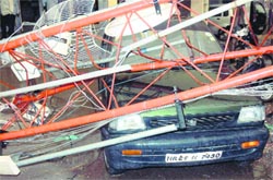A mobile tower collapses on a car during a storm in Faridabad on Saturday.