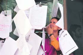 A job aspirant goes through application forms at a book shop on the Canal Road in Jammu