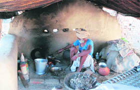 An old man prepares food on a traditional chulha at Dera Sikhligarh in Karnal district. 