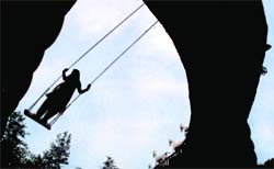 A woman on a swing is silhouetted against a blue sky at Rock Garden, Chandigarh