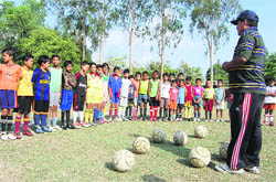 A coach gives tips to young footballers at a camp in Dehradun on Thursday.