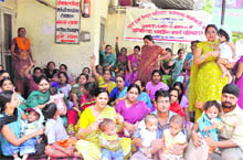 Parents with their infants sit alongside ANM protesters at a hospital in Haridwar on Friday.