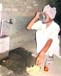 Taking a shortcut: A worker drinks liquor from a public tap at Ahmedgarh