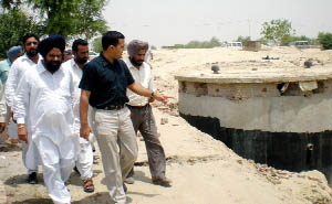 Deputy Commissioner KK Yadav points at a water tank surrounded by sandy heaps close to the Rajasthan border on Saturday.