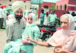A man carries his 90-year-old mother to a polling booth at Panjokhra village in Ambala on Saturday
