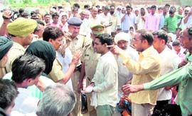 A police officer tries to pacify villagers, who blocked traffic against a murder at Talwara in Fatehabad on Saturday