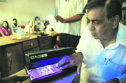 KK Chhabra of the Patanjali Sewa Ashram checks a currency note with the help of a machine for detecting counterfeit currency on Monday.