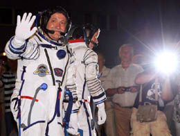 International Space Station crew member Russian cosmonaut Fyodor Yurchikhin (L) waves as US astronaut Shannon Walker walks after putting on their space suits at the Baikonur Cosmodrome.