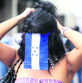 A Honduras supporter adjusts a flag she is wearing after a public screening of their World Cup match against Chile in Tegucigalpa on Wednesday.