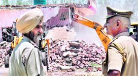 Policemen on duty at the demolition drive site at Raipur Khurd village on Friday.