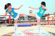Two Chinese promotion girls pose with a World Cup ball to attract visitors to a theme park for watching the televised matches on giant screens in Beijing
