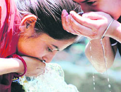 Girls drink water from a roadside borewell in Patiala on Saturday.