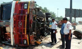 Traffic policemen inspect a truck that met with an accident near Seelampur Metro station in New Delhi on Sunday.