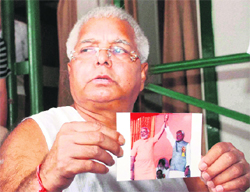 RJD chief Lalu Prasad Yadav shows the controversial picture featuring Bihar CM Nitish Kumar and his Gujarat counterpart Narendra Modi, while addressing a press conference at his residence in Patna on Sunday